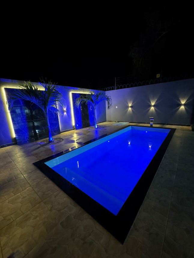 Piscina iluminada em azul à noite com luminárias de parede